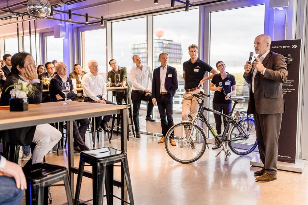 Innovatives Business-Event in München mit inspirierendem Vortrag, moderner Architektur, nachhaltigem Fahrrad, und professionellen Teilnehmern; perfekte Kulisse für Firmenveranstaltungen und Networking.