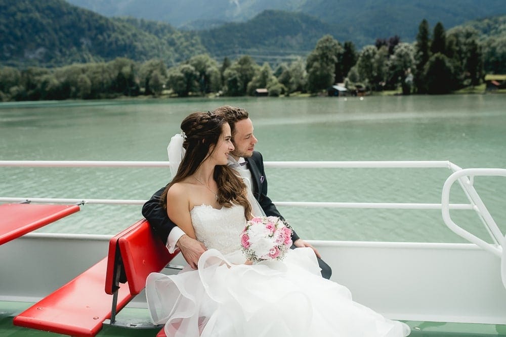 Romantic wedding photo on a boat in Munich, newly married couple with bridal bouquet, beautiful natural scenery, professional photography, wedding photographer Munich, photo studio Photogenika, experiential photography, wedding reportage in Munich.