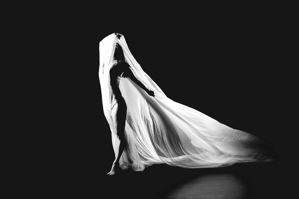 Elegante Fotostudioaufnahme eines Models mit dramatischer Stoffkomposition in schwarz-weiß, professionelle Fotoshootings in München.