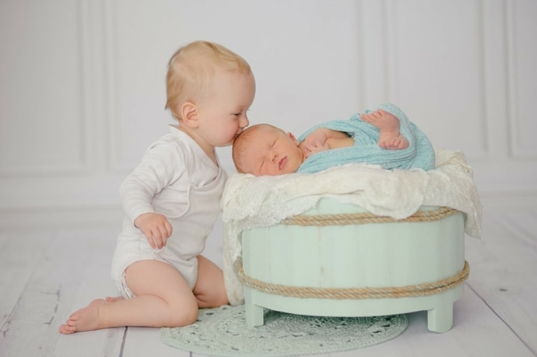 Kleines Kind küsst Neugeborenes in Fotostudio München, liebevolle Babyfotos, professionelle Babyfotografie, newborn Fotoshooting, hochwertige Babybilder, Fotostudio München.