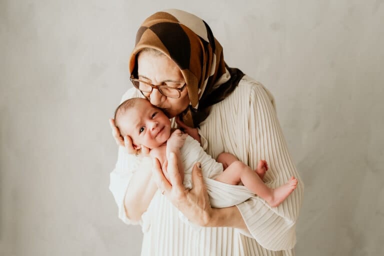liebende Großmutter küsst neugeborenes Baby, liebevolle Familienmoments, zarte Kinderliebe, Naturfotografie, emotionale Familienaufnahme