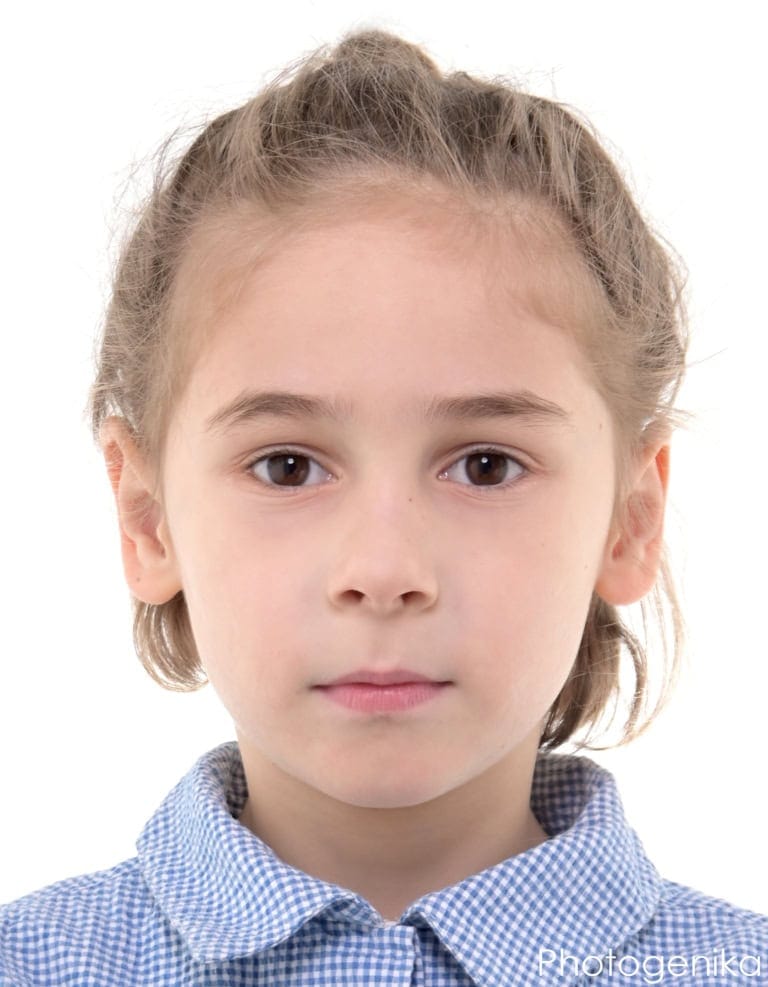 Biometrisches Passfoto eines Mädchens im blau karierten Hemd.